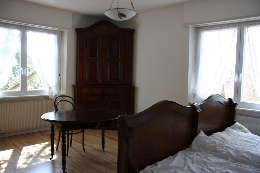 1 dormitorio con cama, mesa y ventanas en Gîte du moulin, en Uhrwiller