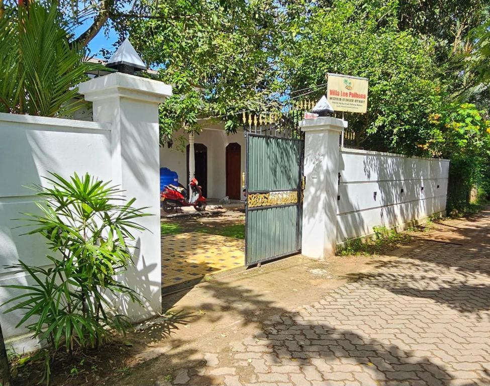 a white fence with a gate with a sign on it at Villa Lee Polhena in Matara