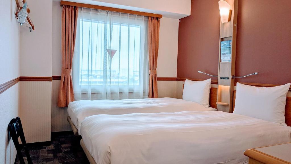 a hotel room with two beds and a window at Toyoko Inn Chubu International Airport No1 in Tokoname