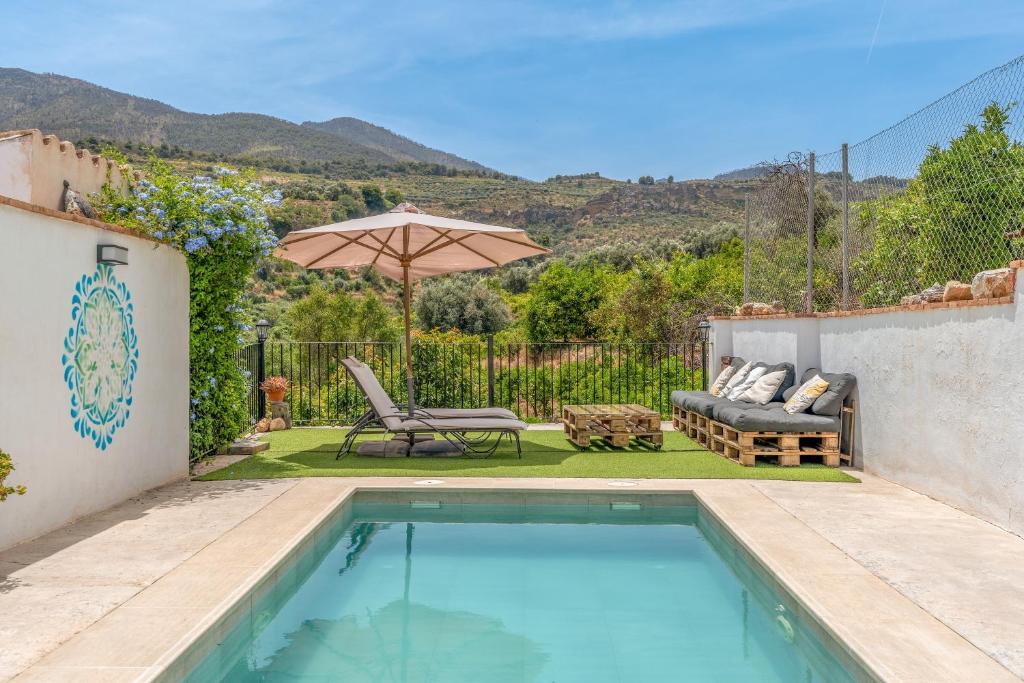 einen Pool mit Terrasse und Sonnenschirm in der Unterkunft Casa con Vistas a Sierra Nevada in Saleres