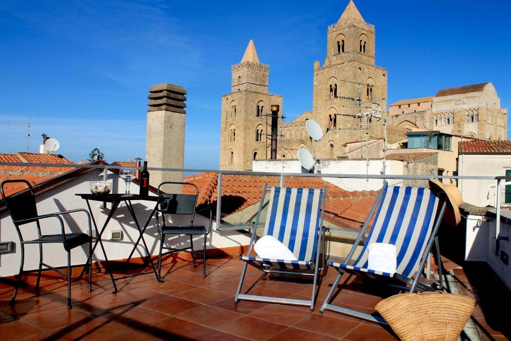 een balkon met stoelen en een tafel op een dak bij Penthouse Duomo in Cefalù