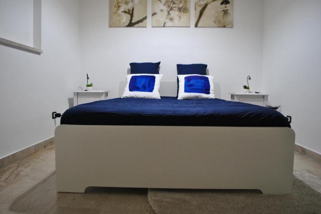 łóżko w białym pokoju z niebieskimi poduszkami w obiekcie B&B Scilla Mare w mieście Scilla