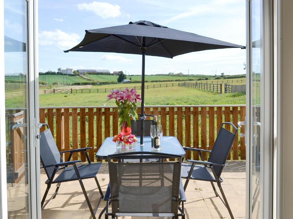 ein Tisch und Stühle mit einem Sonnenschirm auf einer Terrasse in der Unterkunft Hazel Cottage in Shotton