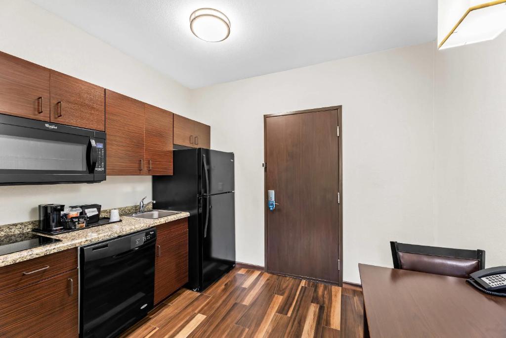 a kitchen with wooden cabinets and a black refrigerator at MainStay Suites Lufkin in Lufkin