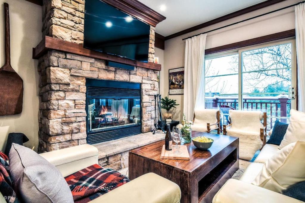 sala de estar con chimenea de piedra en Le Plateau Ski Inout W 3bdrs W Pool Access, en Mont-Tremblant