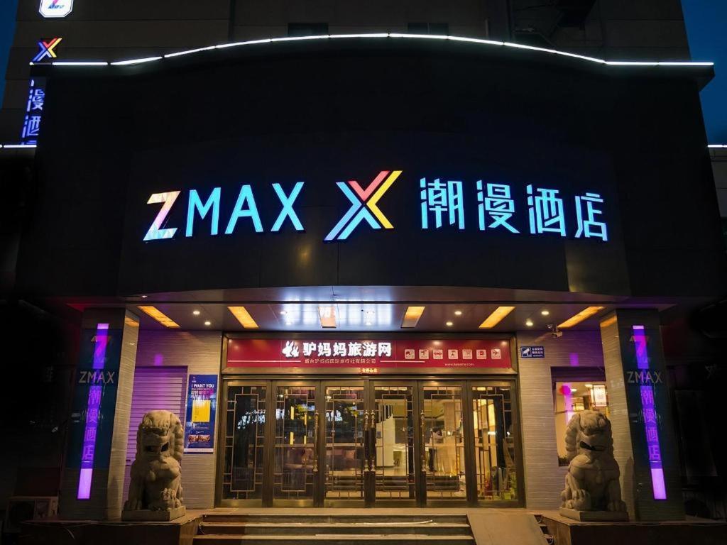 a zmaxx store with two statues outside at night at Zmax Hotel·Yantai Shimao Binhai Plaza in Yantai