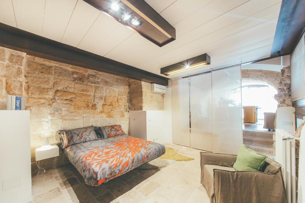 um quarto com uma cama e uma parede de pedra em La pergola em Polignano a Mare
