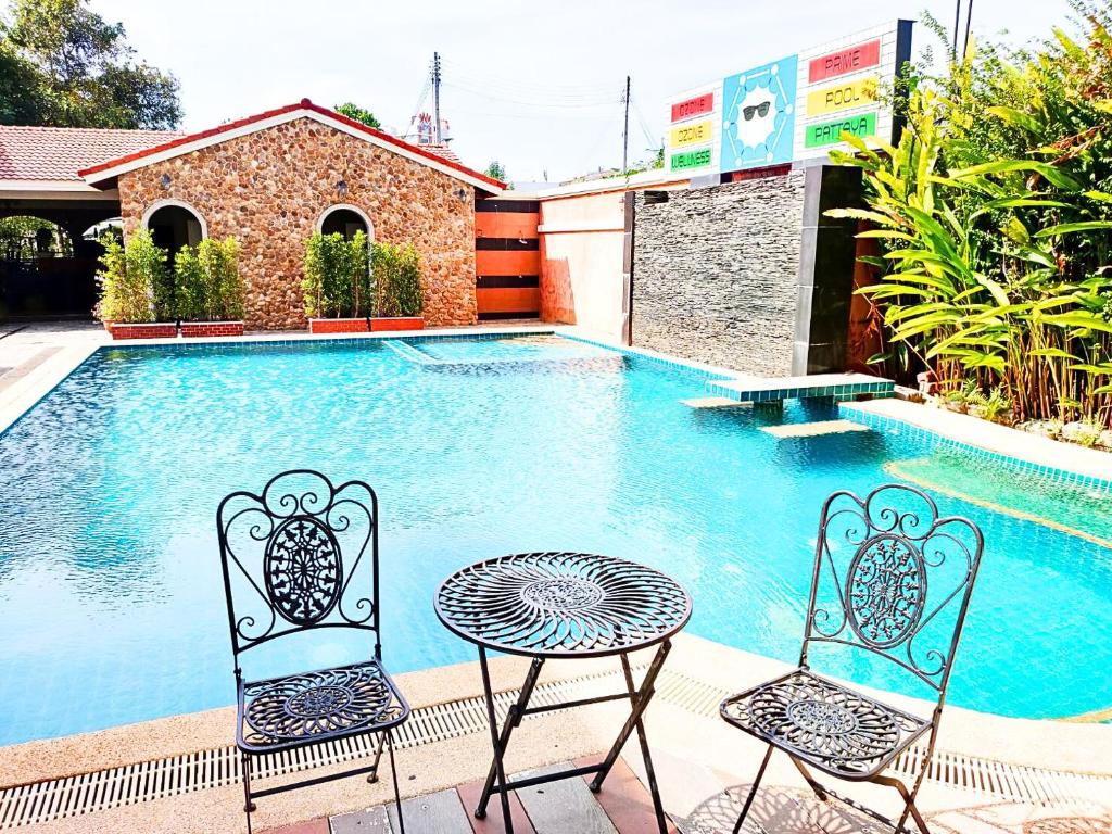 two chairs and a table next to a swimming pool at Welnez World Residence Pattaya in Pattaya Central