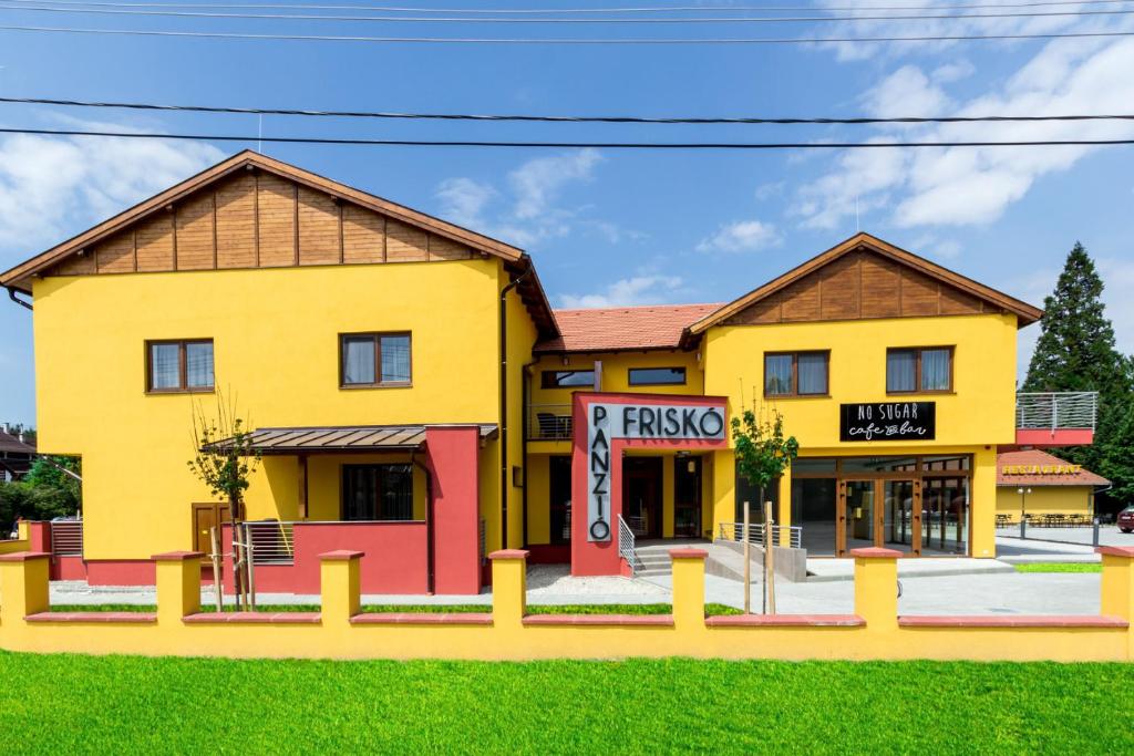 a yellow building with a fast food restaurant at Friskó Panzió in Zalakaros