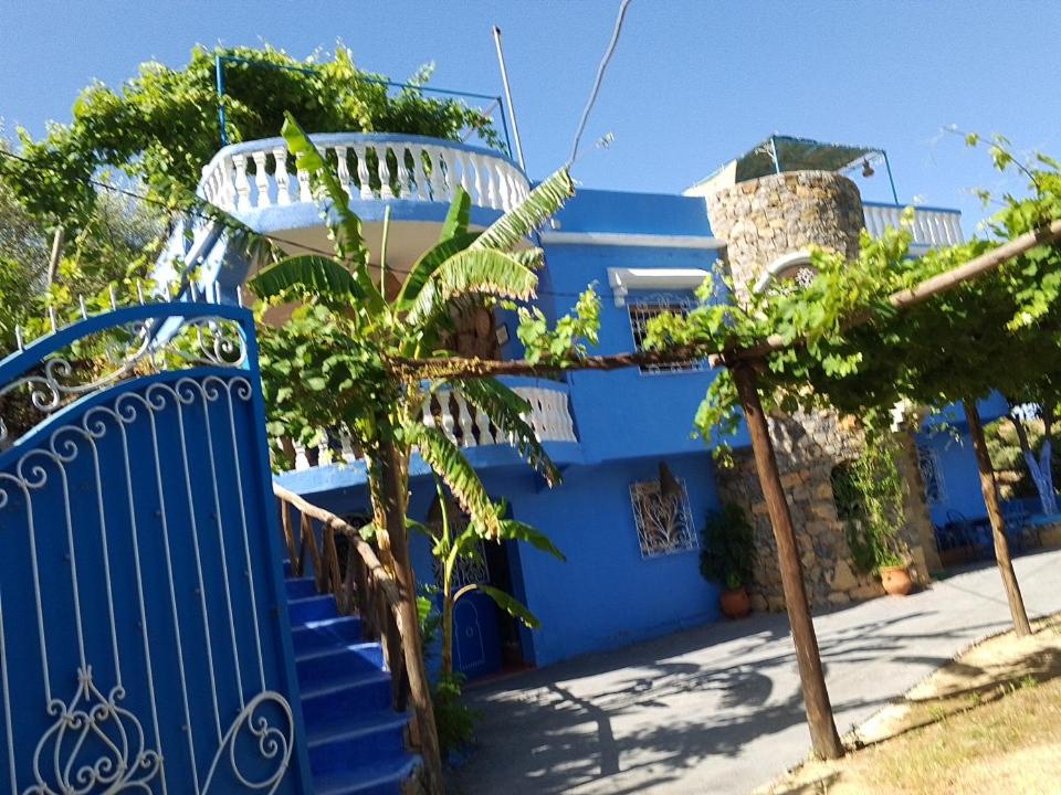 una casa blu con un cancello blu e alcuni alberi di Blue House Town a Chefchaouen