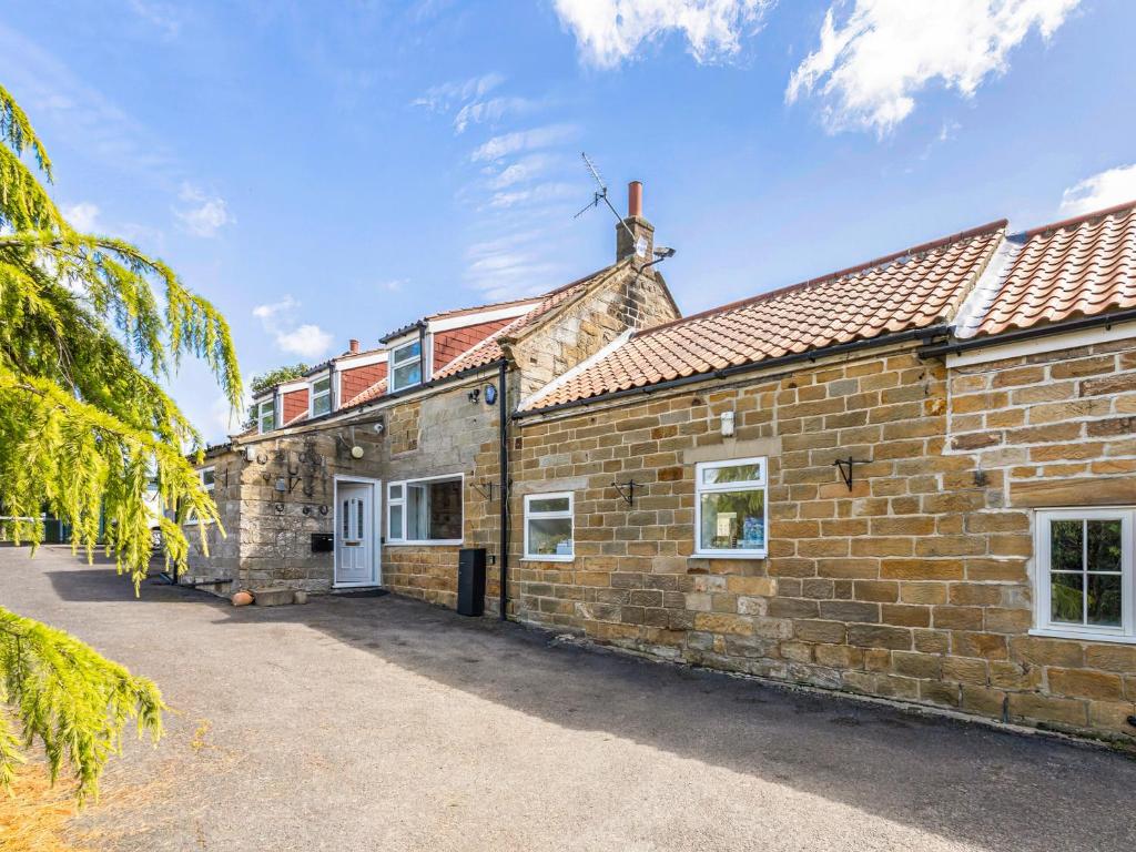 an old brick building with a white door at Rigg Farm Cottage in Stainsacre