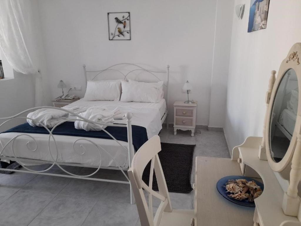 biała sypialnia z łóżkiem i lustrem w obiekcie Sea paradise villas - Seaside & private jacuzzi w mieście Oia