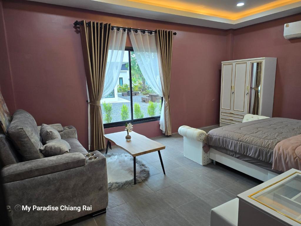 a bedroom with a bed and a couch and a window at My Paradise Chiang Rai in Ban Doi Hang