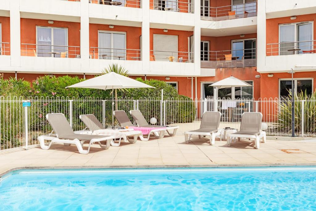 - une piscine avec des chaises et un parasol à côté d'un bâtiment dans l'établissement Appart'City Classic Aix-en-Provence - La Duranne, à Aix-en-Provence