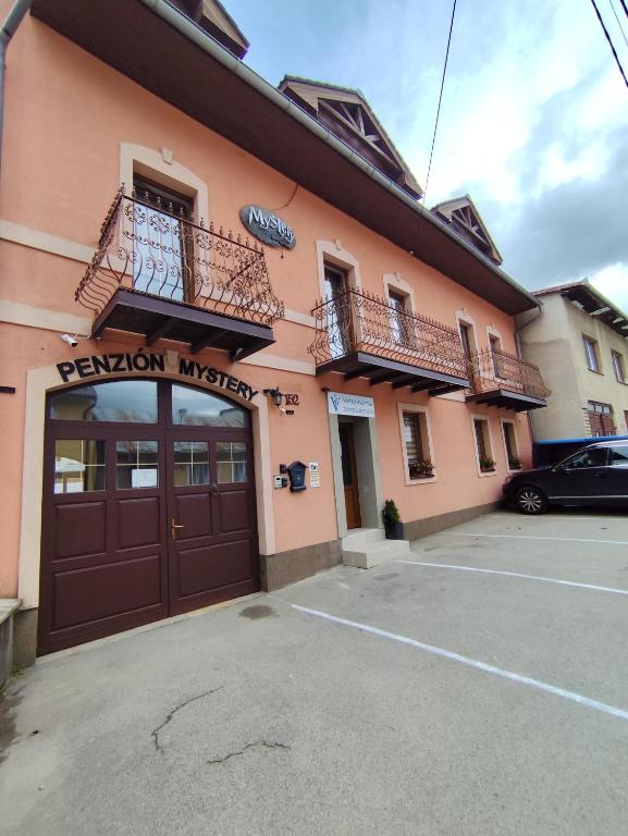 a peach colored building with a garage and a balcony at Penzion Mystery in Vyšné Ružbachy