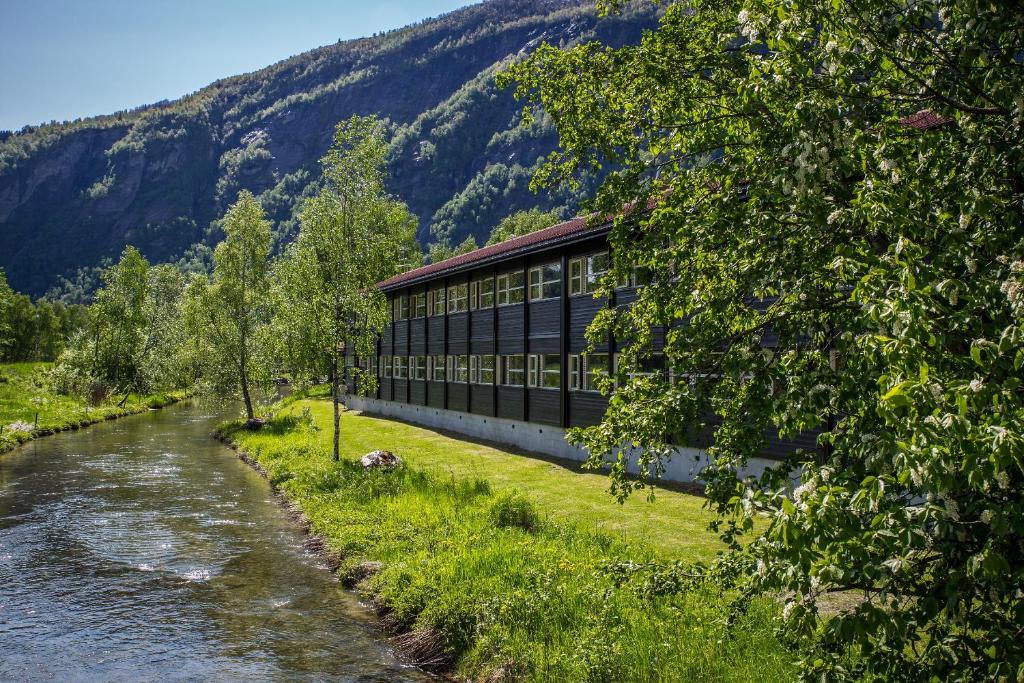 a building next to a river next to a mountain at Gaupnetunet Hotell og Hytter in Gaupne