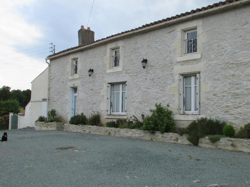a white brick house with a cat sitting in front of it at Les Puvinieres in Breuil-Barret