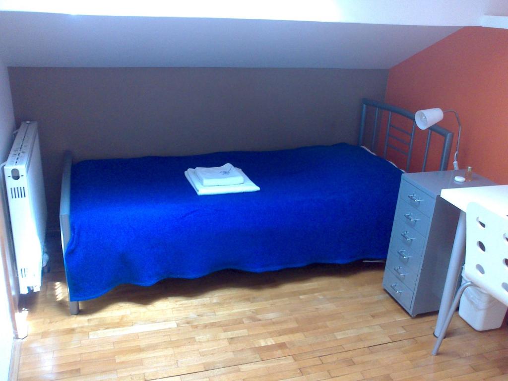 una camera con un letto con una coperta blu e un comò di Rainbow Rooms a Lubiana