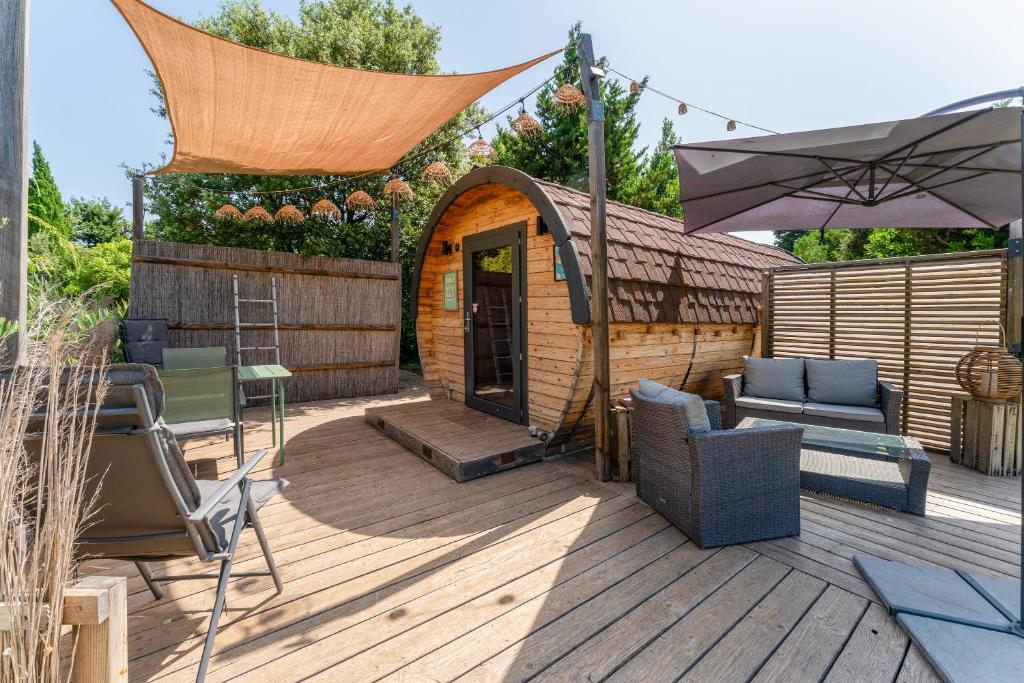 JonquièresにあるTonneau Prestigeの椅子と傘が置かれたガゼボのあるデッキ