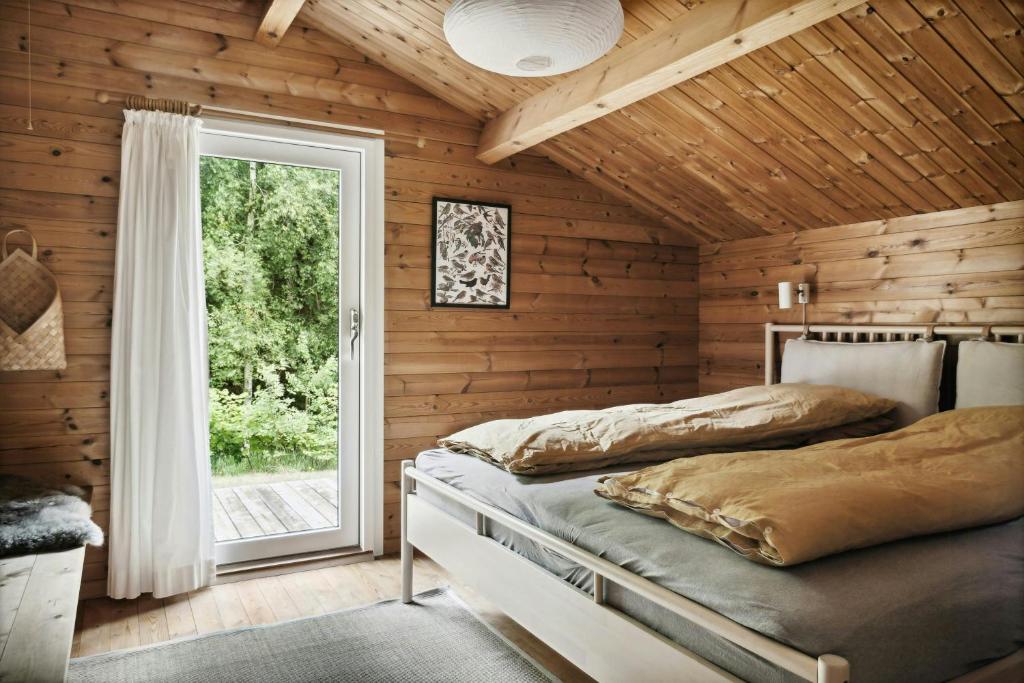 a bedroom with wooden walls and a bed with a window at Simple Life In Traditional Home By Lyngså Beach in Sæby