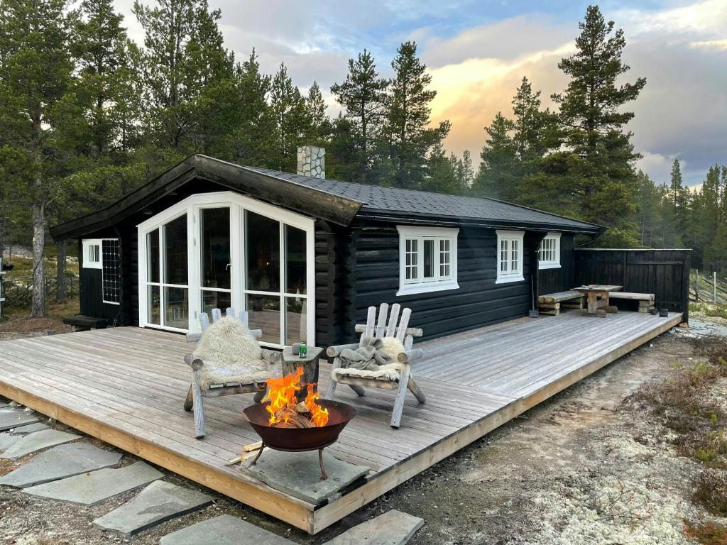 a cabin with a fire pit and chairs on a deck at Log Cabin With Views Of Rondane Mountains in Folldal