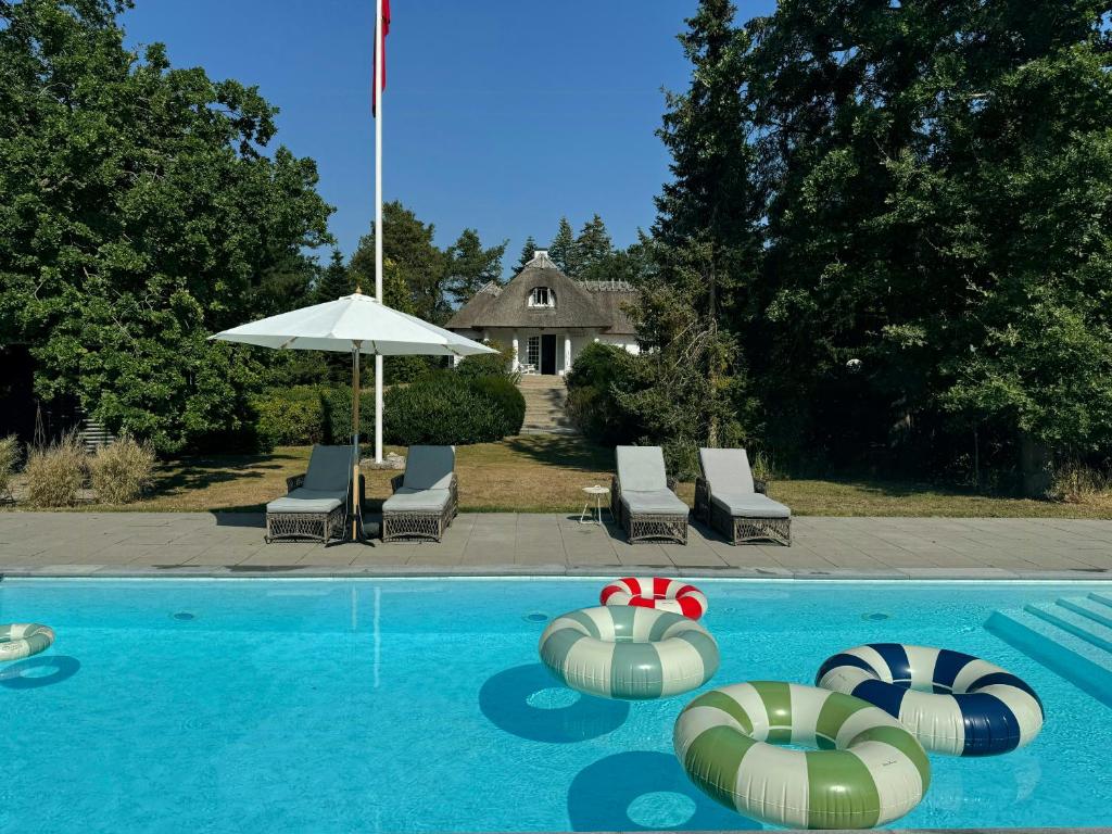 una piscina con due gonfiabili e un ombrellone di Historic Beach Villa With Pool At Marielyst a Bøtø By