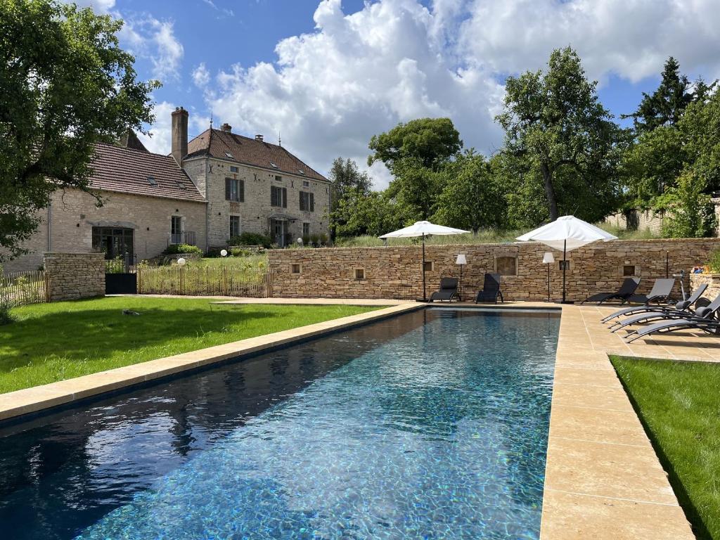 - une piscine en face d'une maison avec des parasols dans l'établissement Clos des Dames de Lancharre, à Chapaize