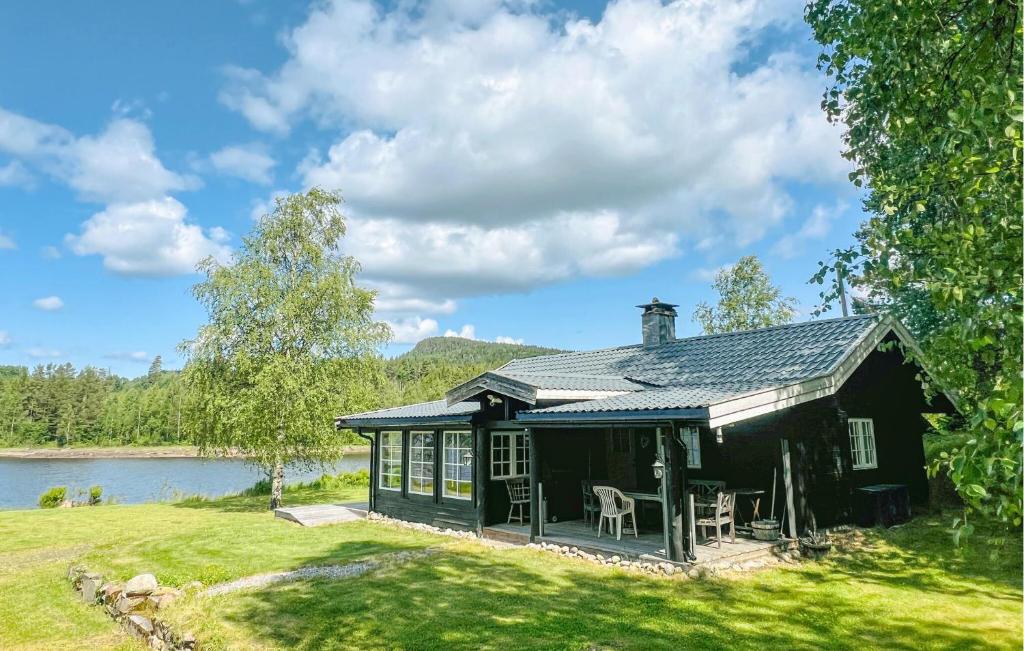 a black house on a lawn next to a lake at 2 Bedroom Awesome Home In Östmark in Östmark
