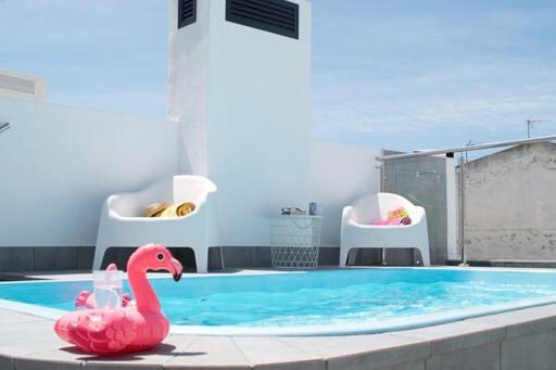 a pink flamingo sitting next to a swimming pool at Edificio Resort Gran8Nerja in Nerja