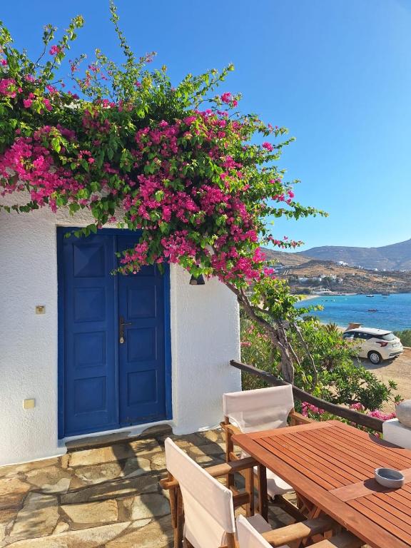 a blue door on a building with pink flowers at Villas Kalafatis Apartments in Kalafatis