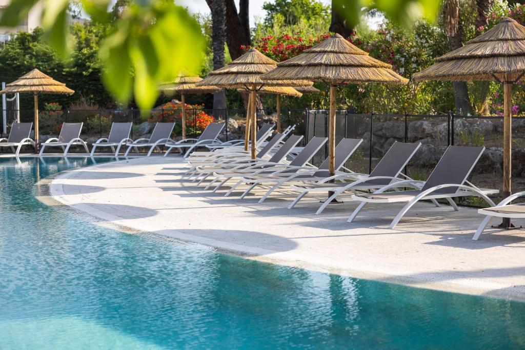 a row of chairs and umbrellas next to a swimming pool at Hotel Club Le Capet in Sainte-Maxime