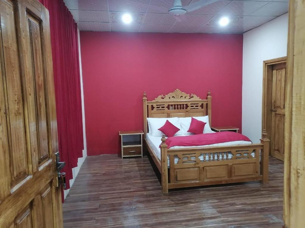 a bedroom with a wooden bed with a red wall at Neelum Lodges & Khan Shinwari Restaurant in Dargai