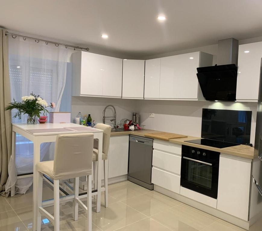 a kitchen with white cabinets and a table and chairs at Comfortable house in Arconsat