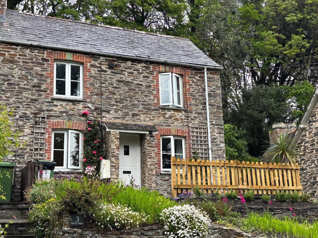 a small brick house with a fence and flowers at Idyllic Cottage near Padstow in Little Petherick