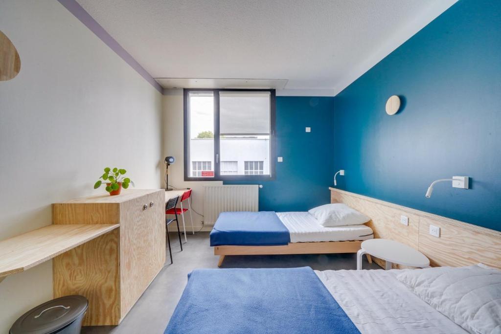 ein Schlafzimmer mit zwei Betten und einer blauen Wand in der Unterkunft Auberge de Jeunesse Barbey - Youth Hostel Bordeaux in Bordeaux