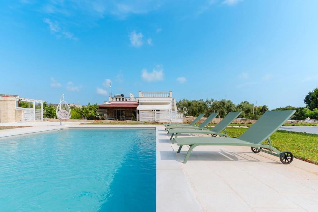 - une rangée de chaises longues à côté de la piscine dans l'établissement B&B L'isola che non c'è, à Torre San Giovanni