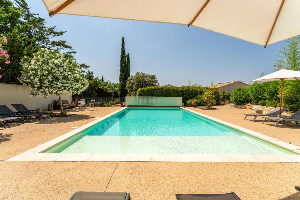 a swimming pool in a yard with an umbrella at Bergeries Saumane, Petite Bergerie in Saumane-de-Vaucluse