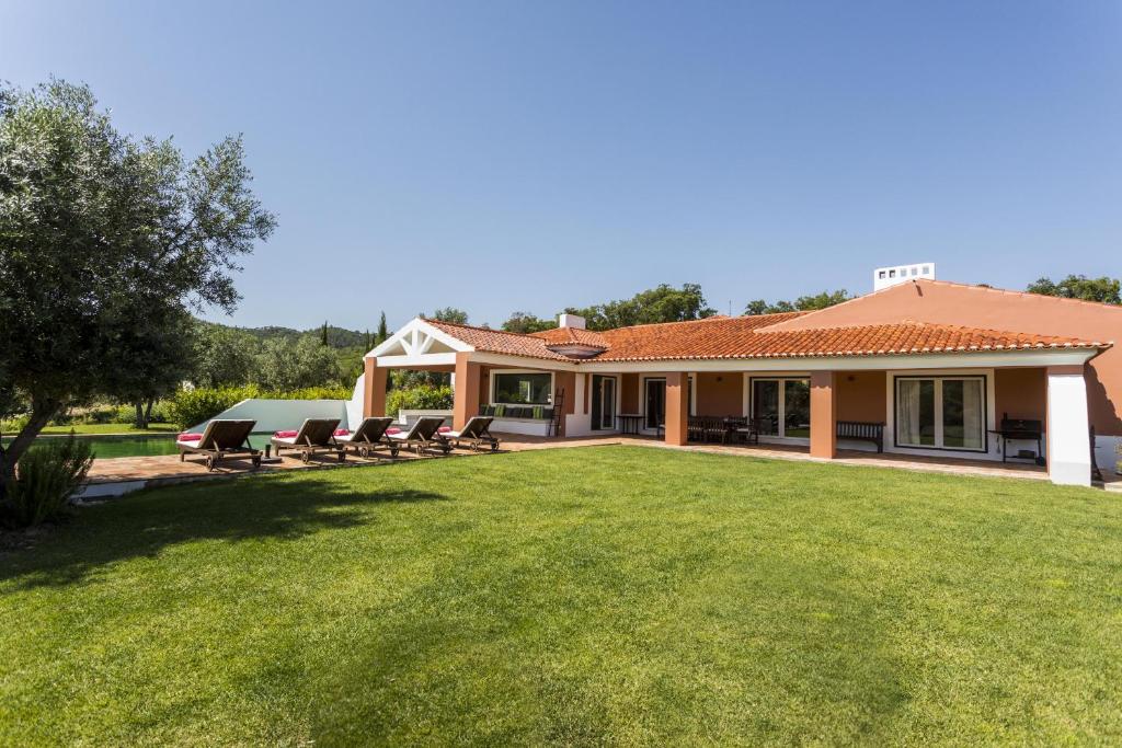 una casa con un gran patio con sillas. en Grandola Mountain Paradise, en Grândola
