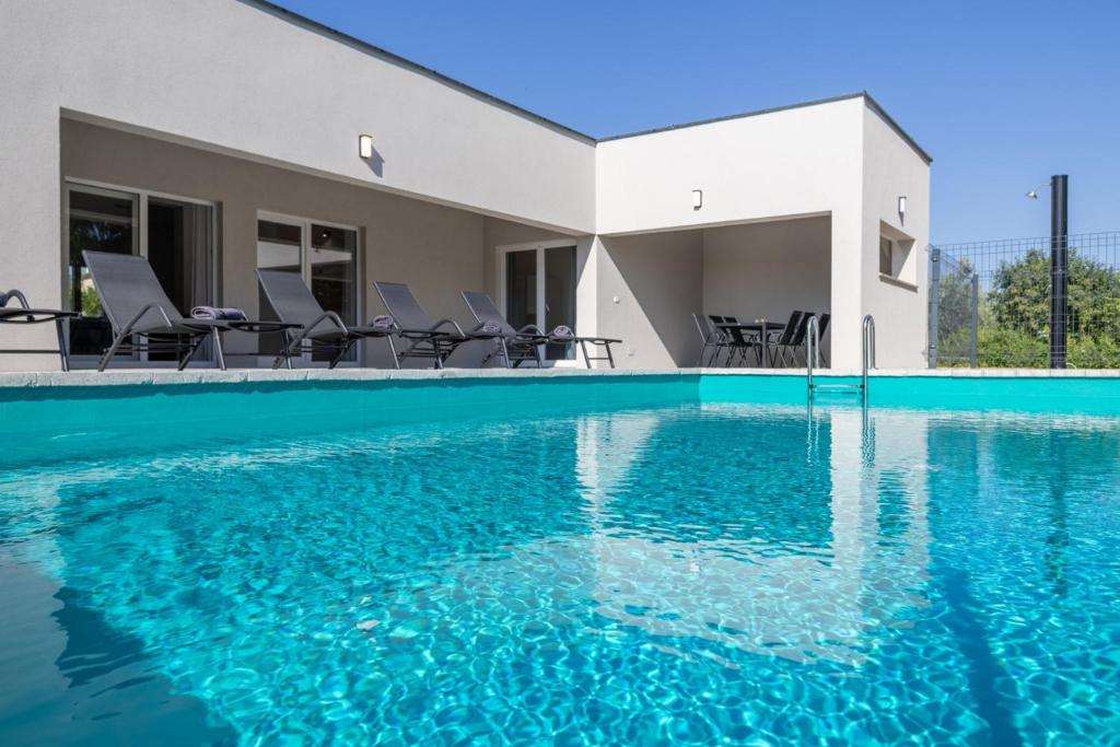 a swimming pool with blue water in front of a house at E&M Forest Retreat in Svetvinčenat