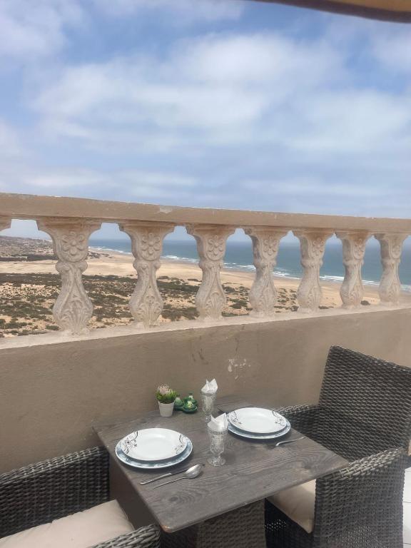 a table on a balcony with a view of the beach at Eco Stay by Ocean Sea View Apartment near Souss Massa National Park in Rbat