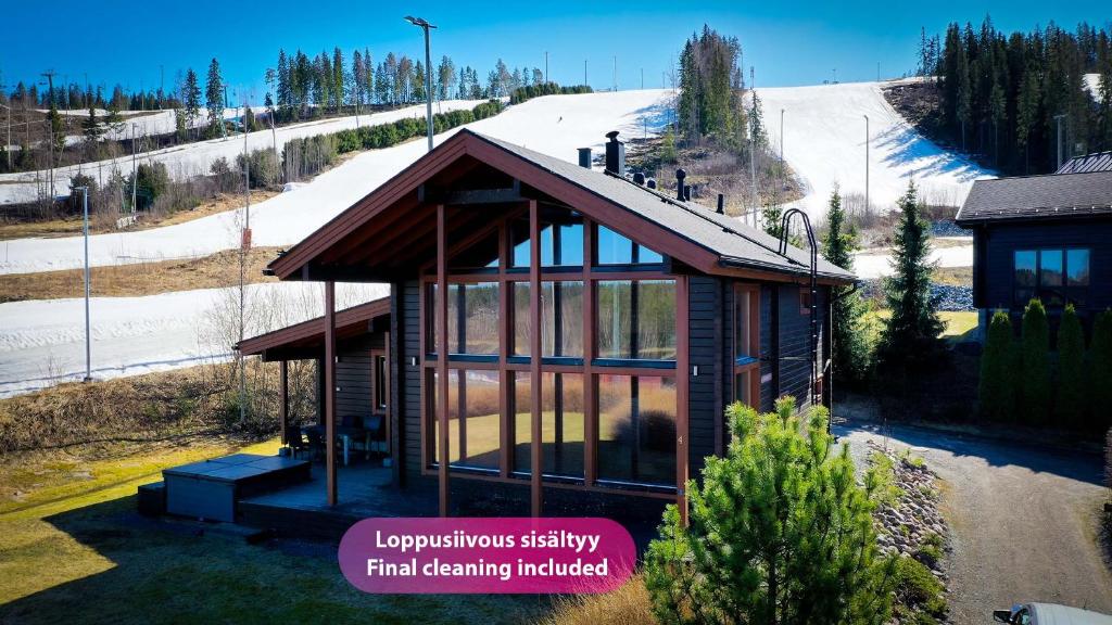 ein kleines Haus mit Glasfenstern auf einem schneebedeckten Hügel in der Unterkunft Villa Lumikki 2 - 8 hlö, Luoteis-Himos Ski-inout in Jämsä