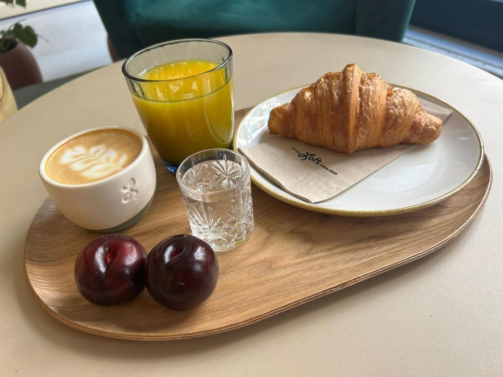 un plateau de petit-déjeuner avec une tasse de café, un croissant et un jus d'orange dans l'établissement The Loft House Madrid, à Madrid