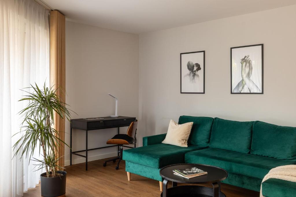 a living room with a green couch and a table at Trevi Apartments Tychy in Tychy
