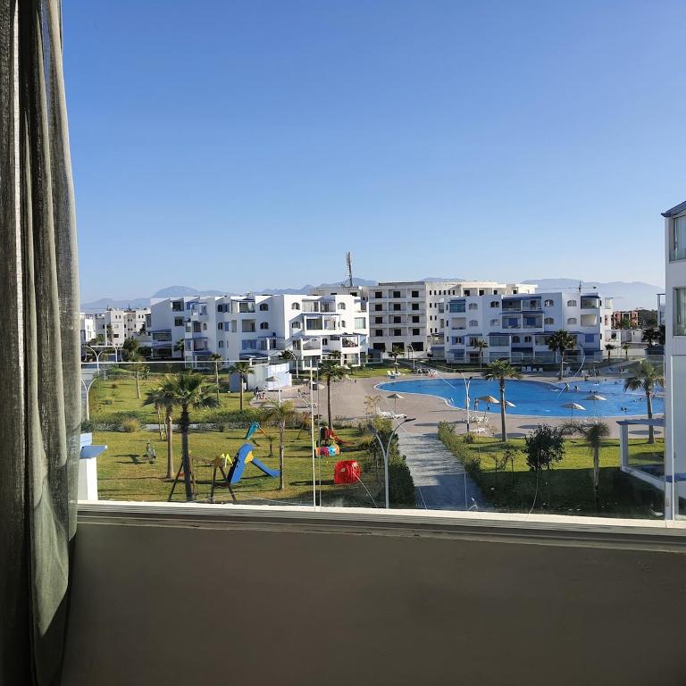 a window with a view of a park and buildings at Superbe apartment en residence with pool in Cabo Negro