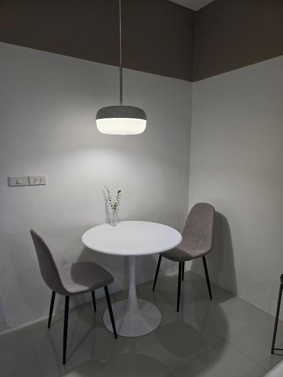 a white table with two chairs and a vase on it at Hommory Residence - Phuket Town in Ban Lo Long