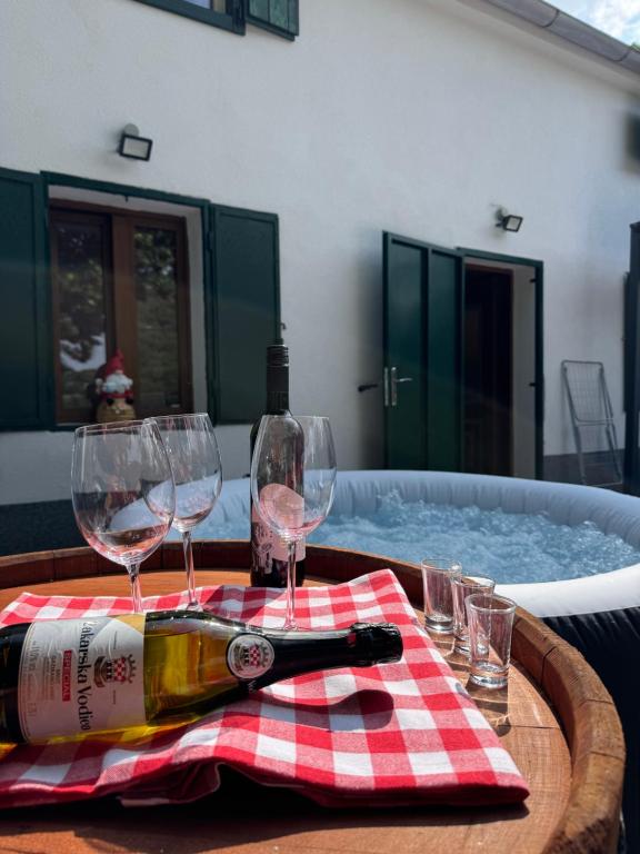 a table with glasses and a bottle of wine and a tub at Kuća za odmor Krasnica in Novi Vinodolski