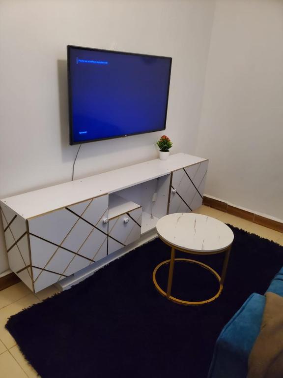 a living room with a tv and a table and a stool at Bright Homes in Eldoret