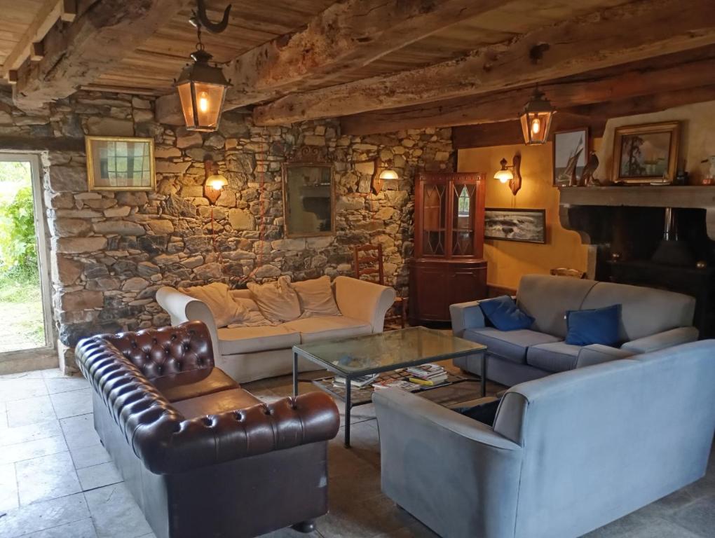 un salon avec des canapés et un mur en pierre dans l'établissement La Maison de Port à la Duc, à Pléboulle