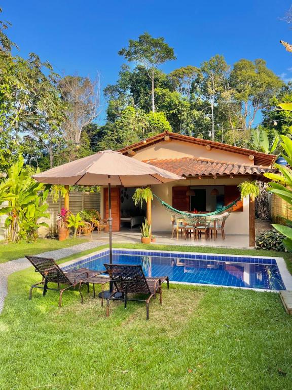a house with a swimming pool with chairs and an umbrella at CASA RENASCER in Trancoso