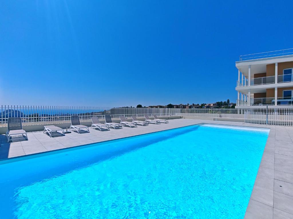 une piscine avec des chaises longues et un bâtiment dans l'établissement BEL AIR Rooftop Pool SeaView, à Villeneuve-Loubet